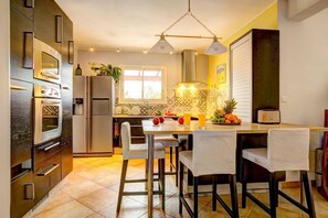 A modern kitchen with stainless steel appliances, a dining area with bar stools, and a window providing natural light.