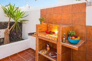 Una cocina con un horno de ladrillo, una planta en maceta y un cuenco con fruta.