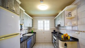 Une cuisine compacte dotée d’un îlot central, d’un four encastré et d’une fenêtre offrant une vue agréable.