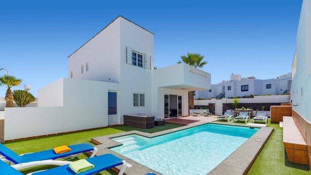 Ein moderner Poolbereich mit rechteckigem Pool, Liegestühlen und einem Gebäude mit flachem Dach.