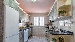 Eine moderne Küche mit Kochinsel, weißen Schränken und einem Fenster.