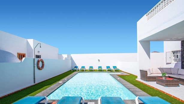 Ein Poolbereich mit Liegestühlen, einem kleinen Pool und einem weißen Gebäude mit Balkon.