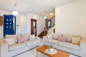 Ein Wohnzimmer mit zwei Sofas, einem Couchtisch und einer Treppe.