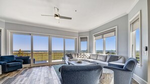 Un balcon spacieux agrémenté d’un canapé moderne, de fauteuils et d’une table basse, offrant une vue sur le paysage.