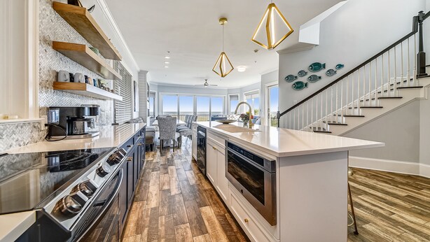 Une cuisine moderne avec des étagères en bois, un îlot central et un escalier menant à un balcon.