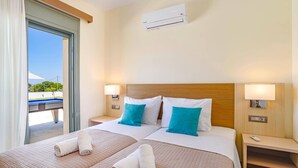 Habitación de hotel con dos camas, un ventanal con vistas, un equipo de aire acondicionado y lámparas de noche.