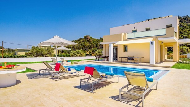 Una casa moderna de dos pisos con piscina, mobiliario exterior y un jardín bien cuidado.