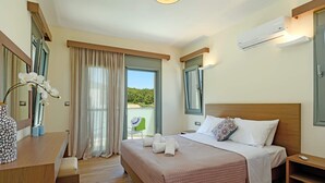 Et hotelværelse med seng, sengeborde, et skrivebord, en stol, et vindue med gardiner og en aircondition.