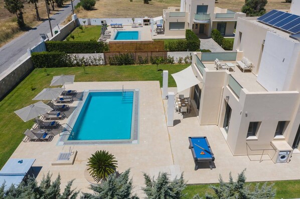 A modern residential complex with a central swimming pool, outdoor seating, and solar panels.