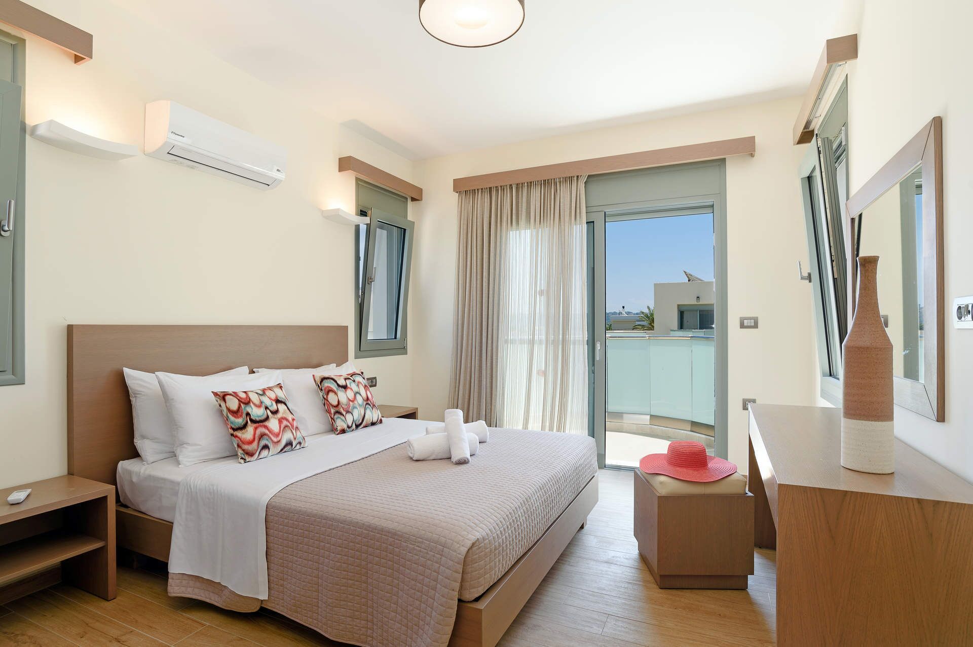 Een moderne hotelkamer met een groot bed, nachtkastje, dressoir en een balkon met uitzicht.