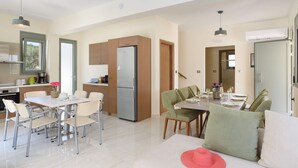 A modern kitchen with a refrigerator, stove, and dining area with chairs and a table set for two.