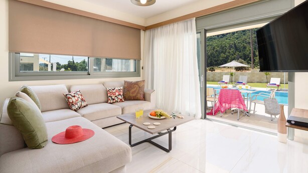 A modern living room with a sofa, coffee table, and a view of an outdoor pool area.