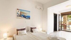 Une chambre à coucher comprenant un lit, des oreillers, une table de chevet, un tableau, un appareil de climatisation et une vue sur l’extérieur.