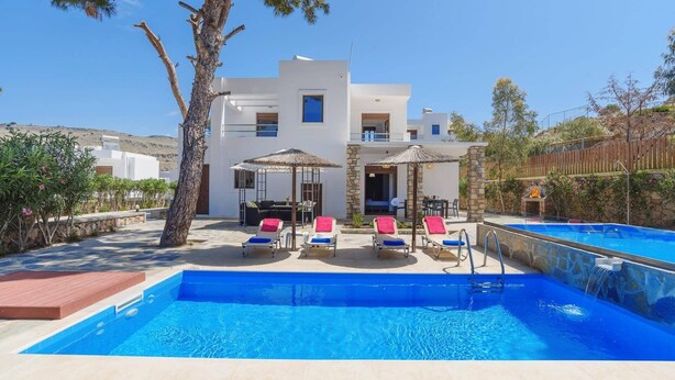 Une villa moderne dotée d’une piscine, d’un espace extérieur aménagé et d’un mur en pierre.