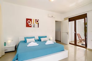 A bedroom with a bed, a nightstand, a wall art piece, and a sliding glass door leading to a balcony.