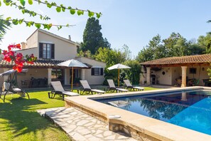 Une piscine avec des chaises longues, un espace patio et un bâtiment doté d’un toit en tuiles.