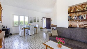 A spacious living area with a dining table, chairs, a sofa, and a bookshelf. - Villa Rosanna by Villa Plus (Fontane Bianche)