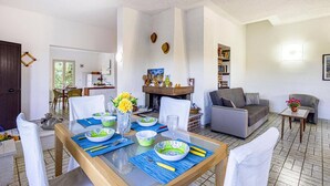 A dining area with a table set for four, a fireplace, and a living room with a sofa and armchairs. - Villa Rosanna by Villa Plus (Fontane Bianche)