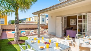 A patio with a table set for breakfast, outdoor seating, and a pool. - Villa Atenas by Villa Plus (Adeje)