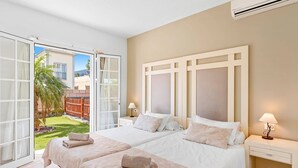 A hotel room with two beds, a large window, and an air conditioning unit. - Villa Atenas by Villa Plus (Adeje)