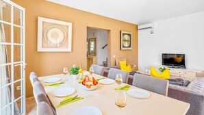 A dining area with a table set for four, a television, and a staircase leading to another room. - Villa Atenas by Villa Plus (Adeje)