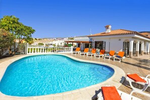 A swimming pool with lounge chairs, a white building with a tiled roof, and a clear blue sky. - Villa Blanca Salvaje by Villa Plus (Callao Salvaje)
