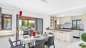 A modern kitchen with white cabinets, a black countertop, and a dining area with a round table and chairs.