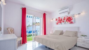 Une chambre à coucher avec un lit, une table de chevet, une commode et une fenêtre avec des rideaux rouges.