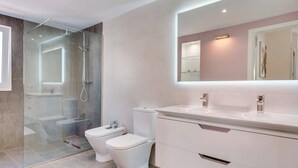 A modern bathroom with a glass shower enclosure, two toilets, a large mirror, and a white vanity. - Villa Colibri by Villa Plus (Palm-Mar)