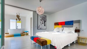 A modern bedroom with a large bed, a bathtub, and a colorful headboard. - Villa Colibri by Villa Plus (Palm-Mar)