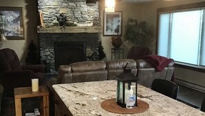 Un salon chaleureux avec une cheminée en pierre, un canapé en cuir et une table à manger en marbre.