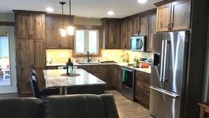 Une cuisine moderne avec des meubles en bois, des appareils électroménagers en acier inoxydable et un îlot central.