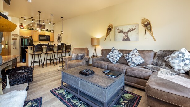 Ein Wohnzimmer mit braunem Sofa, einem Couchtisch und einem Essbereich mit Stühlen und einer Bar.