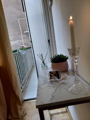 A marble table with a white candle, a glass candle holder, a small potted plant, and a decorative item.