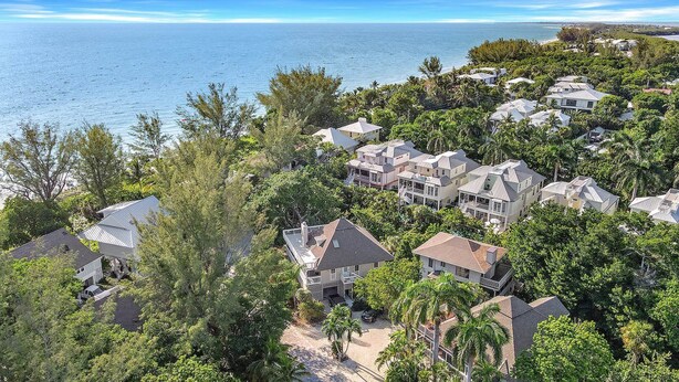 A coastal residential area with houses surrounded by dense greenery and a view of the ocean. - Sunset Captiva 10 (Captiva)