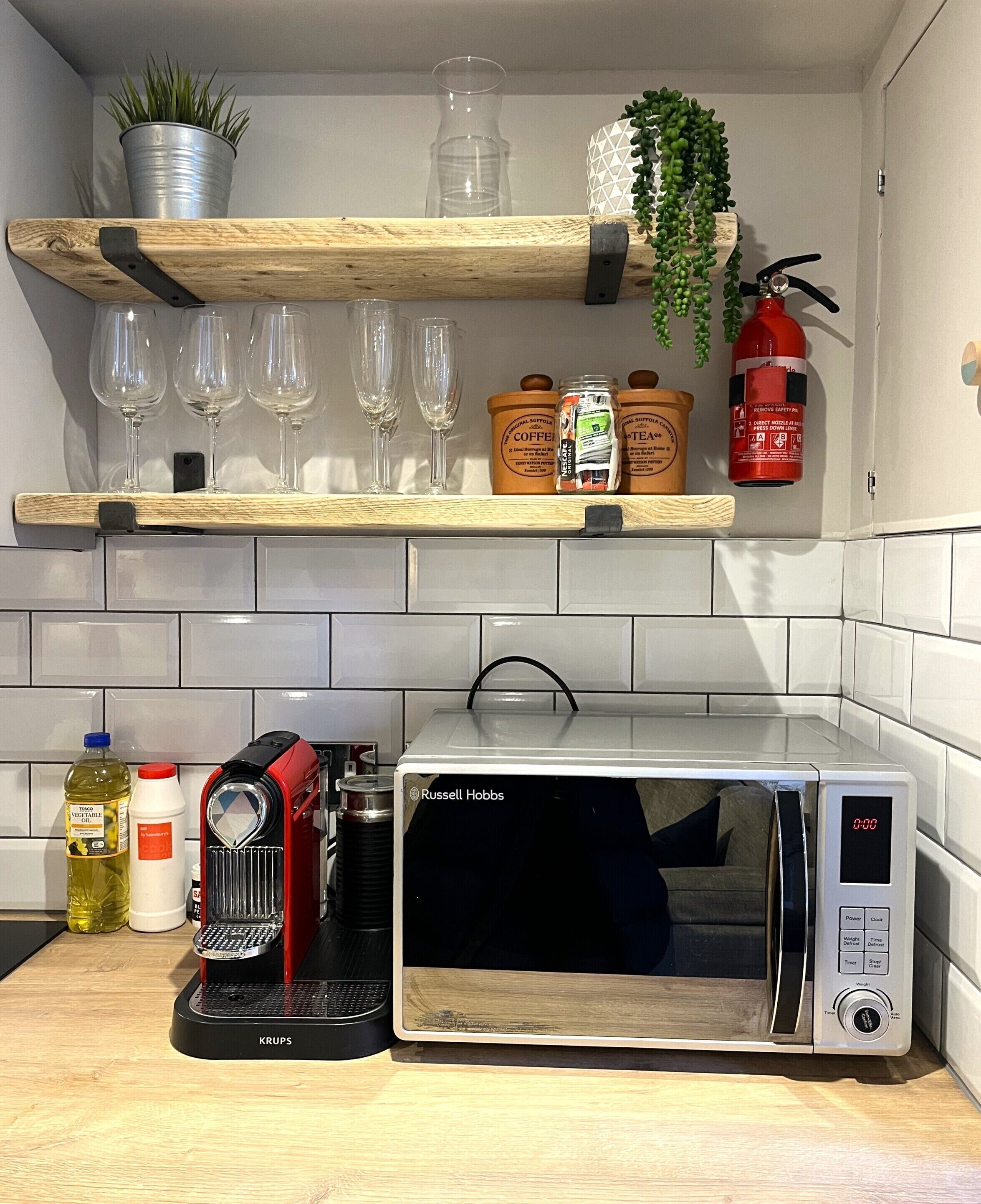 A kitchen with a microwave, a coffee machine, and various kitchen items on the counter.