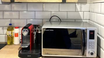 A kitchen with a microwave, a coffee machine, and various kitchen items on the counter.
