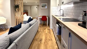 A modern kitchen with a wooden countertop, a built-in oven, and a sink. - Stylish Studio Apartment in Clifton Village (Bristol)