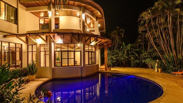 A modern house with a pool, large windows, and a well-lit interior. - Tamarindo Grand Villa. Oasis at walking distance to Tamarindo Beach! (Tamarindo)