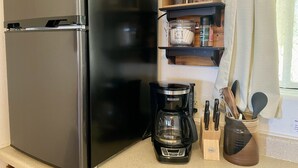 A kitchen with a black refrigerator, a coffee maker, and a wooden shelf with jars and utensils. - Sunrise Suite - Sierra Mountain Lodge (Ahwahnee)