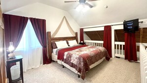 A bedroom with a bed, a ceiling fan, a TV, and a window with curtains. - Sunrise Suite - Sierra Mountain Lodge (Ahwahnee)
