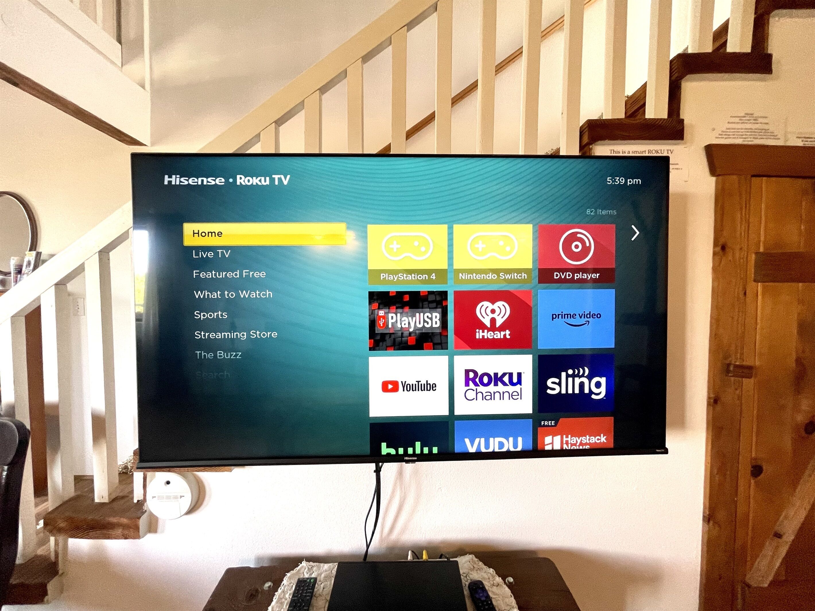 A television screen displaying a Roku TV interface with various streaming service icons.