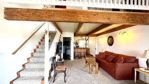 A spacious living area with a staircase, a red sofa, and a wooden coffee table. - Sunrise Suite - Sierra Mountain Lodge (Ahwahnee)