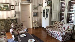 Un soggiorno con divani a motivi floreali, un tavolino da caffè con piatti e un mobiletto con vetrate.