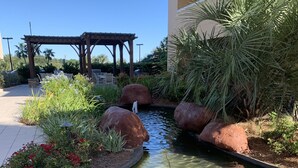 Un jardin aménagé avec un petit étang, des rochers et différentes espèces de plantes.