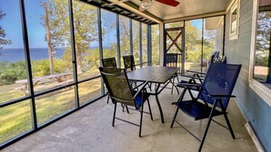 A covered patio with a table and chairs, large windows, and a ceiling fan. - Poco's Retreat                                . (Many)