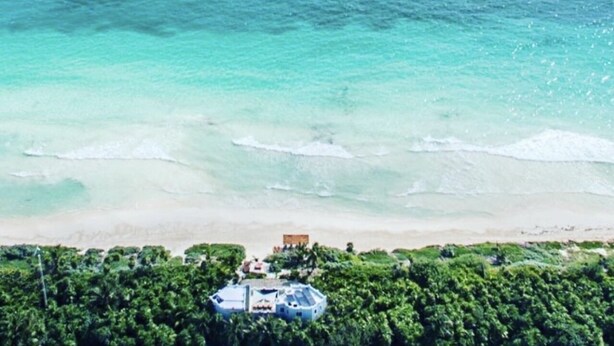 An aerial view of a coastal area with a clear blue sea, a sandy beach, and a small building surrounded by dense green vegetation. - TULUM Beachfront 20min from hotel zone <br>Housekeeping - amazing food (Tulum)