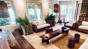A spacious living area with a large wooden table, two sofas, and a coffee table. There are potted plants and a hanging light fixture. - TULUM Beachfront 20min from hotel zone <br>Housekeeping - amazing food (Tulum)