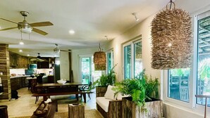 A spacious living area with a wooden bench, a sofa, and a dining table. There are potted plants and a hanging light fixture. - TULUM Beachfront 20min from hotel zone <br>Housekeeping - amazing food (Tulum)