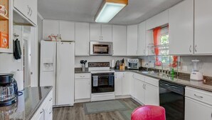 A modern kitchen with white cabinets, a microwave, oven, and dishwasher. - White Oak 4BR @ Patterson Place (Durham)